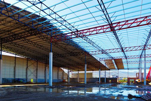 Girders and struts of a warehouse being built form a lattice.