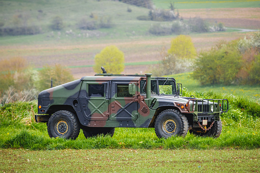 Münsingen, Germany - May 1, 2023: AM General HMMWV Humvee four-wheel drive military utility vehicle on a country road on a sunny summer day.