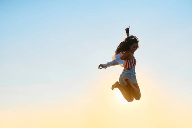 istock Young woman having fun while jumping against the sky at summer sunset. 1492050142