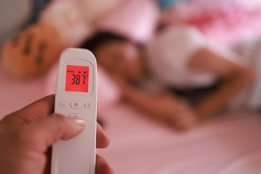 Sick thermometer, child health and mother reading fever, care for girl with covid and check on virus in bed of house. Kid resting with flu while mom takes temperature in bedroom of home with love