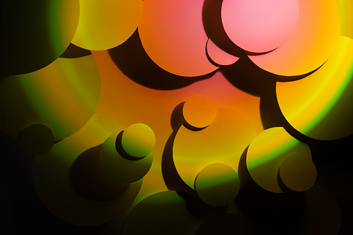 Bright abstract texture with circles in hard gradient light of pink and yellow color with deep shadows and darkness in summer sunny sunset color or fantasy disco 90s style.