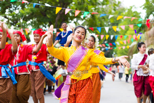 Close portrait of group of red  and golden dressed Rum thai dancing women Close portrait of group of red  and golden dressed Rum thai dancing women with headscarf at Traditional thai festival in street in Phitsanulok in midnorthern Thailand. Women are dressed in golden and  red  traditional clothing and are dancing rum thai while walking along street. There different dressed groups of women. Public local traditional culture event organized by local government. Performance band is dressed traditionally and playing ancient music true thailand classic stock pictures, royalty-free photos & images