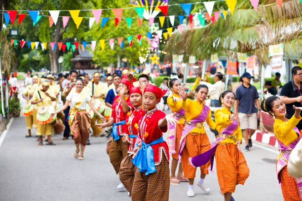 Traditional thai festival Traditional thai festival in street in Phitsanulok in midnorthern Thailand. Women are dressed in traditional clothing and are dancing rum thai while walking along street. There different dressed groups of women. Public local traditional culture event organized by local government. Performance band is dressed traditionally and playing ancient music true thailand classic stock pictures, royalty-free photos & images