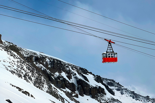The gondola cabin is lifted by a cable car. Funicular. Landscape of snow-capped mountains. A mountain peak. Extreme sports.