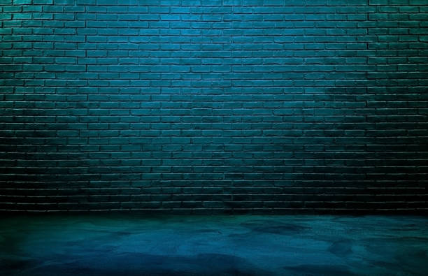 istock dark black brick wall background, rough concrete and plastered concrete floor, with neon blue glowing lights from above. lighting effect blue and green on empty brick wall background for design. 1492058838