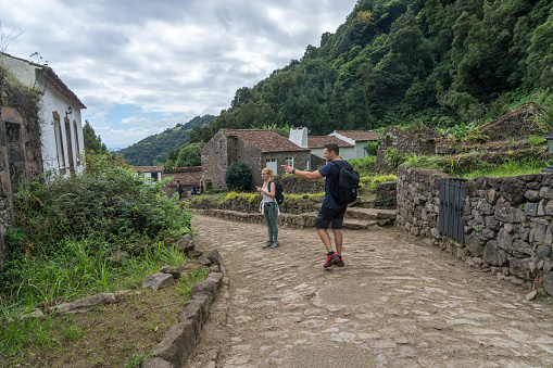 Two tourists on stone street in old, abandoned village in Faial da Terra, the path to the waterfall Salto De Prego. Sao Miguel island in Azores