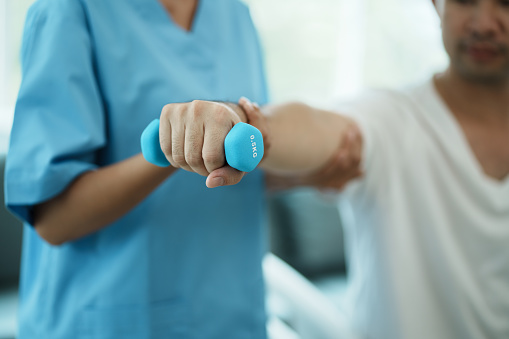 Physiotherapist treating rehabilitation arm pain patient doing physical therapy exercises.