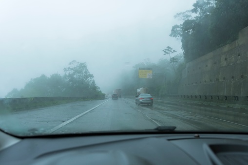 Car and truck traffic on the highway on a cloudy day with fog and rain. Climbing the mountain on the Rodovia dos Imigrantes, São Paulo, Brazil. A driver's point of view.