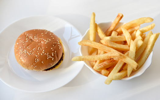 Hamburger on a plate and French fries. Delicious fast food breakfast.