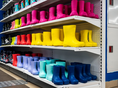 Shelves in the store with rubber boots . Boots of different colors, a large selection for children and adults. All the colors of the rainbow. Shoes in rainy weather.