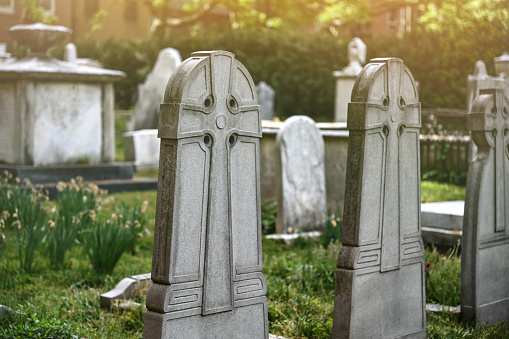 Woman sitting at grave with hand on grave