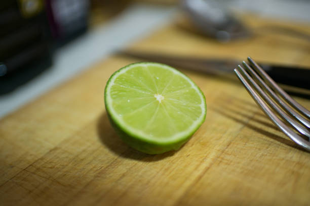 Close up of half lime on a wooden cutting table. Metal fork