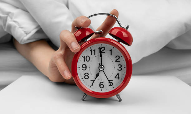 istock Woman's hand turning off red alarm clock on night table 1492083671