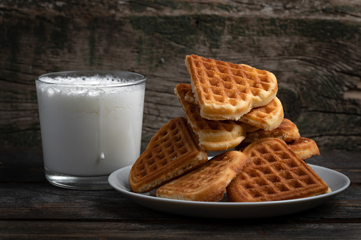 plate with Viennese waffles cookies and glass of milk on rustic wooden background. Heart shape form biscuits cookies