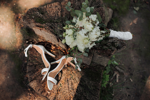 bridal bouquet and high heel shoes on tree stump