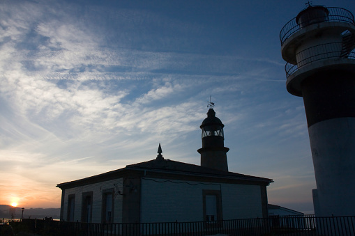 Ancient lighthouses outlined, sunset sky, sunbeam background  in San Cibrao, A Mariña, Lugo province, Galicia, Spain.