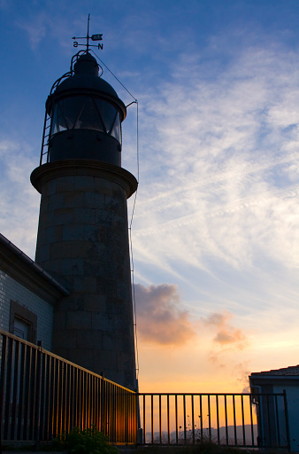 Ancient lighthouse outlined, sunset sky background  in San Cibrao, A Mariña, Lugo province, Galicia, Spain.