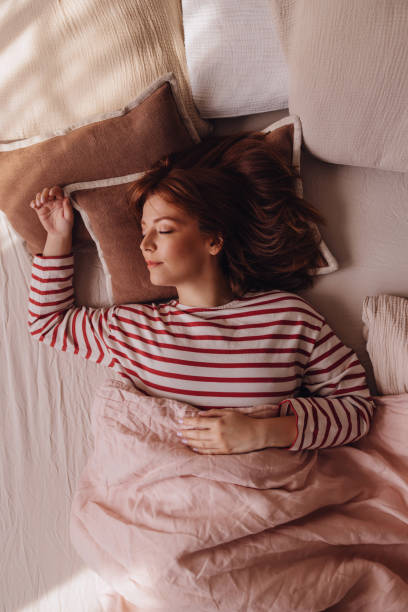 bella donna di zenzero che giace nel suo letto, dormendo in un fine settimana - red bed foto e immagini stock