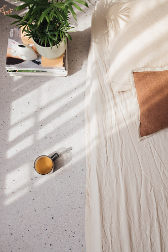 An overhead shot of a cup of coffee on the floor of a bright bedroom.