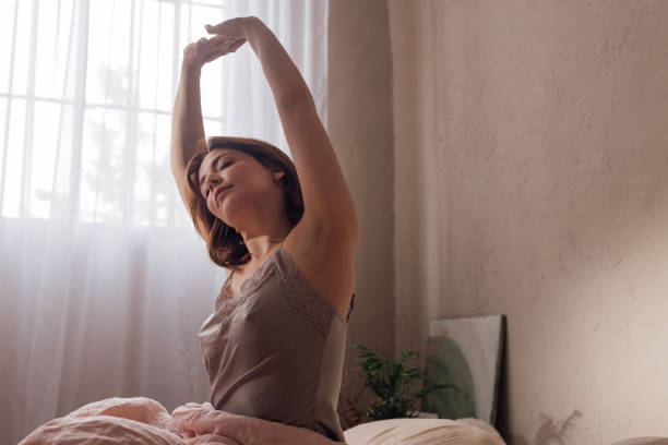 istock Morning Routine: Beautiful Ginger Woman Stretching her Back while Sitting on her Bed 1492087764