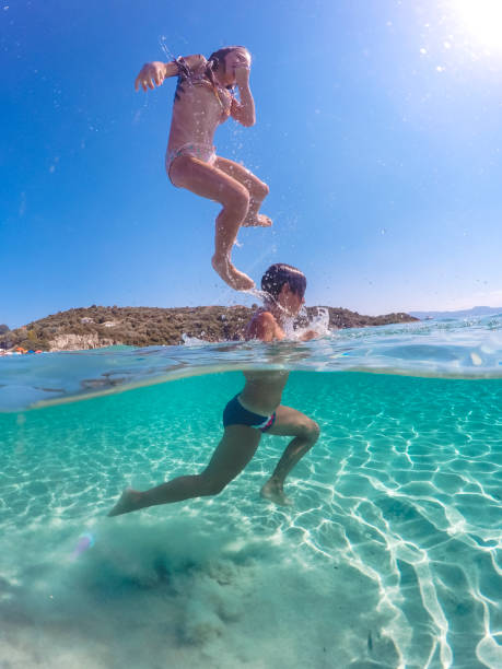 istock Children having fun jumping in to clear sea 1492087818