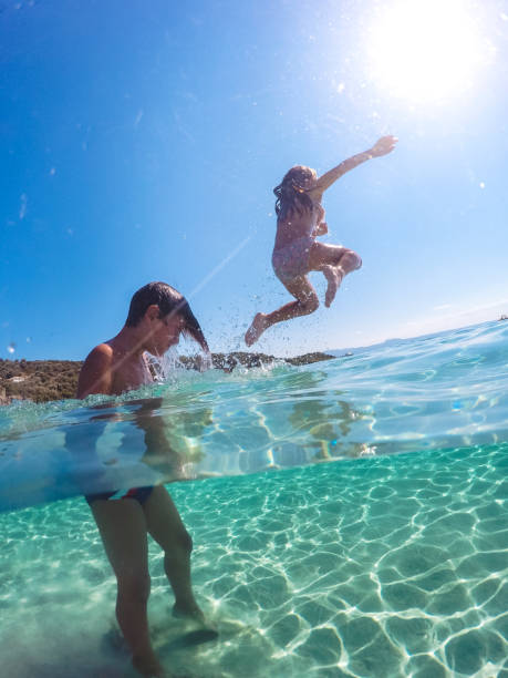 istock Children having fun jumping in to clear sea 1492087886