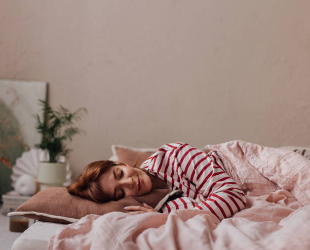 bella donna di zenzero che giace nel suo letto, dormendo in un fine settimana - red bed foto e immagini stock