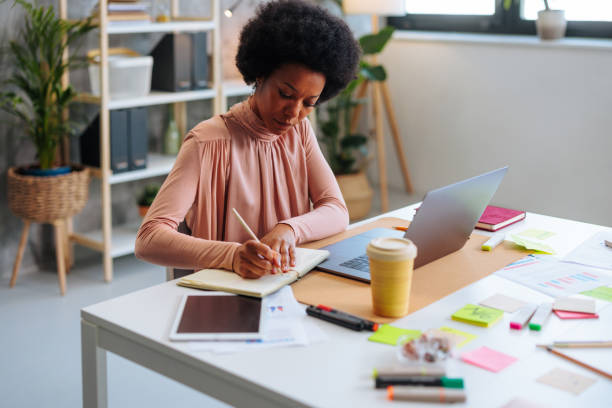 istock African-American business woman writing in notebook while working in office. 1492089635