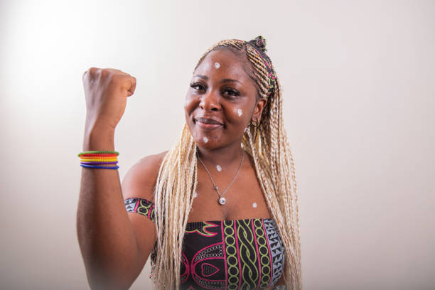 una ragazza lesbica africana con il braccio alzato mostra i bicipiti e indossa un braccialetto arcobaleno - gay pride wristband rainbow lgbt foto e immagini stock