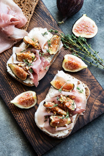 istock Breakfast with figs, cream cheese and  ham  toasts on a wooden board 1492092473