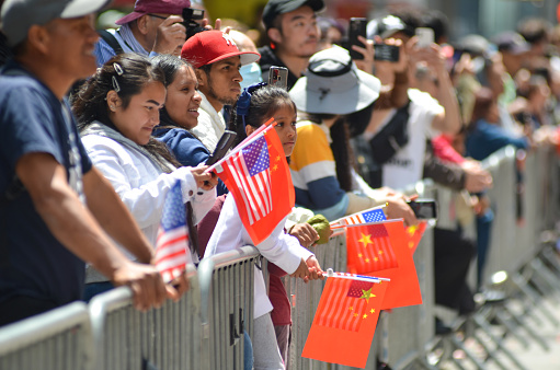 Spectators holding Chinese and USA flags on Sixth Avenue during the Asian American and Pacific Islander Cultural and Heritage Parade in New York City, on May 21, 2023.