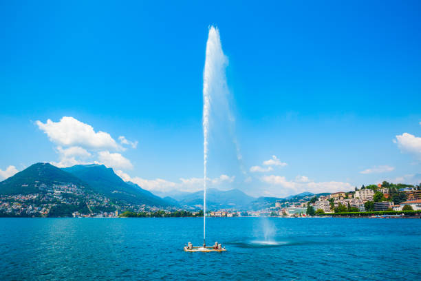 Fountain at Lugano lake and Lugano city panoramic view in canton of Ticino in Switzerland