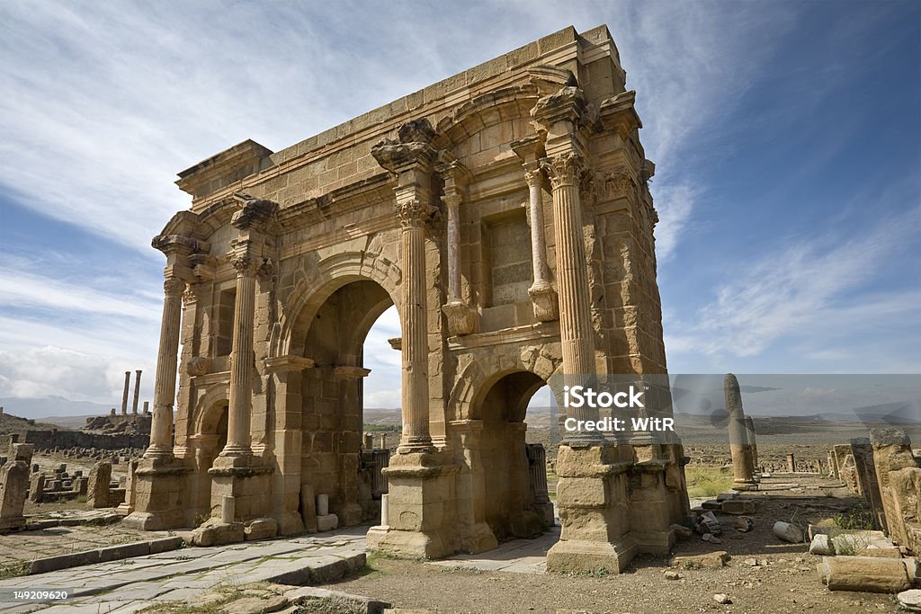 The Arch of Trajan Algeria. Timgad (ancient Thamugadi or Thamugas). Triumphal arch, called Trajan's Arch (Corinthian order with three arches) and fragment of Decumanus Maximus street. Please see my other images of the Roman sites in Tunisia, Libya, Jordan and Syria Africa Stock Photo