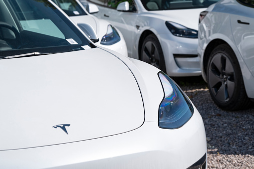 Berlin, Germany - 11 May, 2023: White electric Tesla Model 3 cars parked on a public parking. This model is one of the most popular electric cars in the world.
