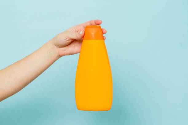 istock Woman's hand holding packaging of shampoo or conditioner on blue background. Copy space and mock up 1492102889