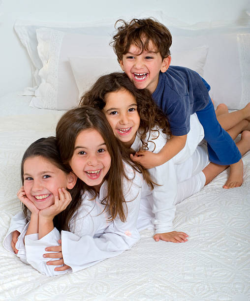portrait of three children lying on the bed. Sisters and brother smiling while looking at the camera. High quality photo