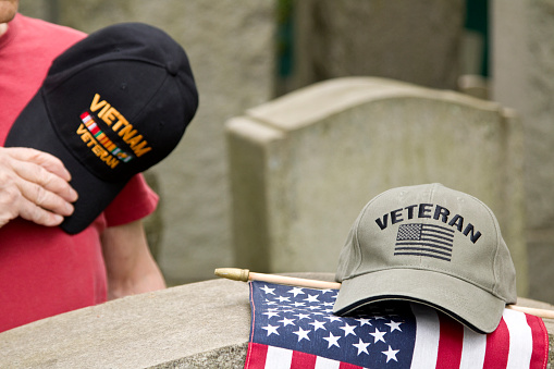 Vietnam Veteran in cemetery honoring fallen comrade.