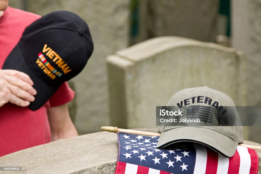 Vietnam Veteran hat over heart saluting deceased solider Vietnam Veteran in cemetery honoring fallen comrade. Respect Stock Photo