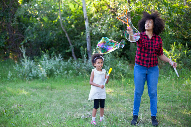 istock Happy mother and her daughter playing soap bubbles in park. 1492110609