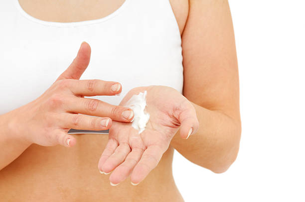 Woman spreading hydrating cream on her hands stock photo