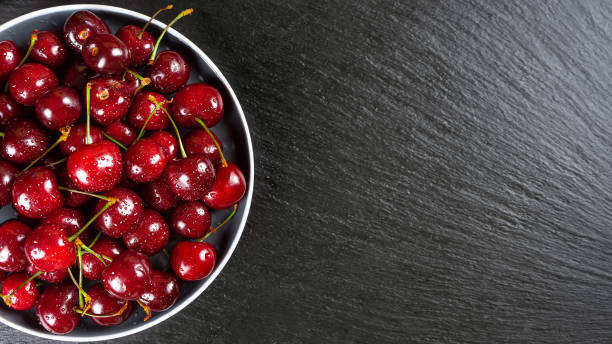 istock Fresh red ripe sweet cherry on plate on black slate background. 1492129964