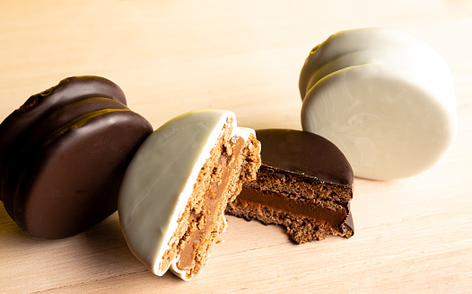 Artisanal alfajores of cornstarch with coconut, white chocolate and dark chocolate with dulce de leche on wooden mat