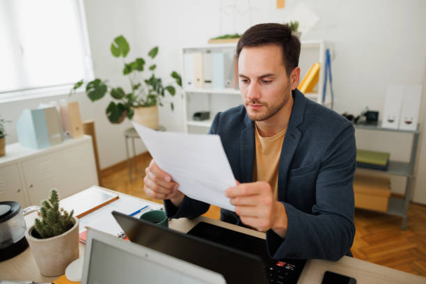 istock Young concentrated businessman reading document in modern home office 1492137962