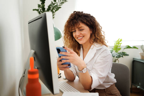 istock Smiling well dressed businesswoman using phone while working at modern home office 1492137975