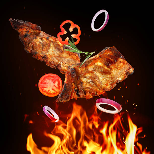 istock Tasty grilled meat, different vegetables and fire flame on dark background 1492140043