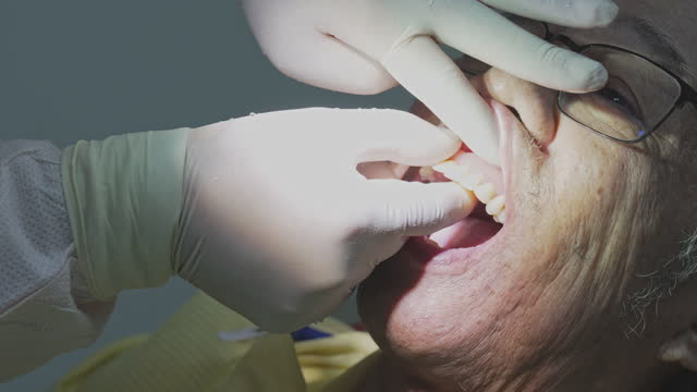 Dentist inserting denture on patient Asian Chinese senior man 's mouth
