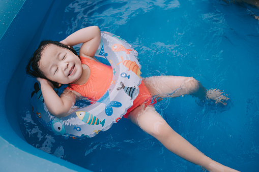 asian chinese baby girl enjoying me time in inflatable swimming pool