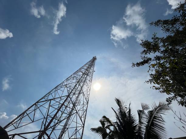 station de la tour de haute télécommunication avec fond de ciel bleu ensoleillé dans la zone d’un village urbain tropical avec des feuilles de palmier et d’arbre - sky tree audio photos et images de collection