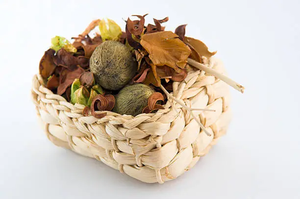 Still life of woven straw basket filled with potpourri on white background