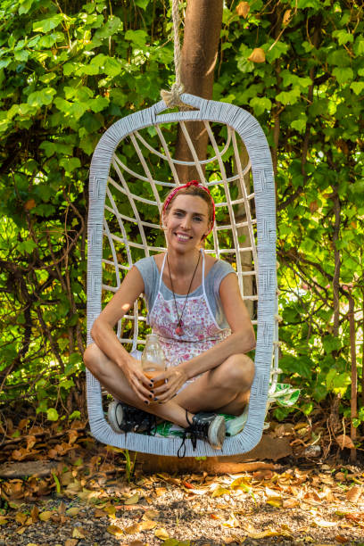 istock Smiling entrepreneur at her juice shop backyard resting on swing chair while drinking fresh detox juice 1492164286